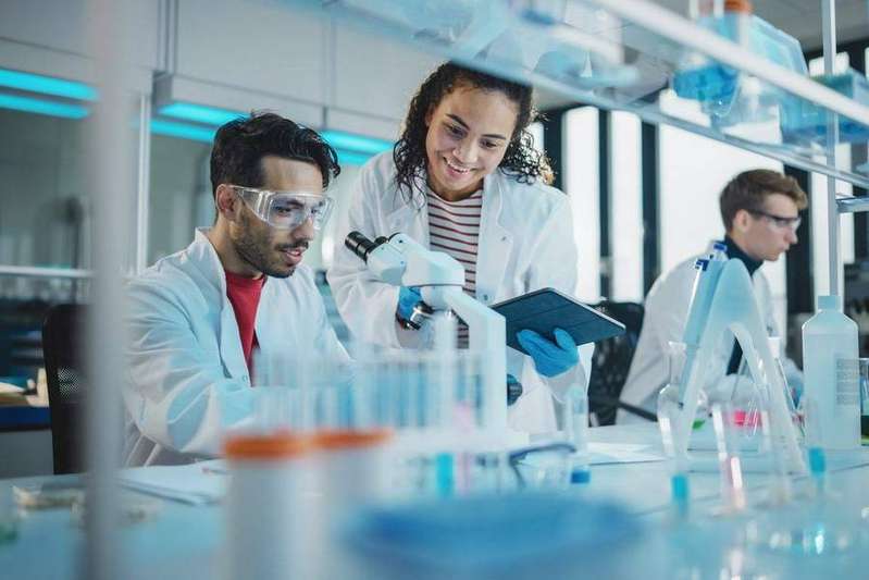 Scientists collaborating at a microscope in a research lab